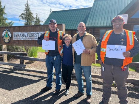 Christian Hansen (left), President Mary C. Daly, Steve Rigdon (center), and Michael Hogarty (right) display their one word descriptions of Yakama Nation. The one word descriptions are Honor, Epic, and Resilient, respectively.