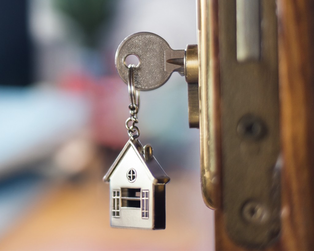 Key with a house on keychain unlocks an open door.